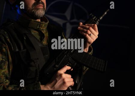 Gros plan d'un soldat en uniforme militaire avec arme sur fond noir. Banque D'Images