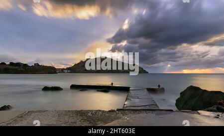 Petite jetée dans un ciel nuageux et une mer laiteuse avec le fond du château et de la ville de Myrina sur l'île de Lemnos. Banque D'Images