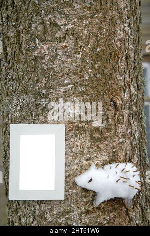 Approche créative des enfants. Les enfants ont coincé une figure de neige d'un hérisson sur un arbre (comme un relief élevé). Cadre en bois Banque D'Images