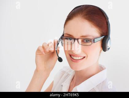 Service avec le sourire. Un jeune télévendeur parle sur son micro-casque. Banque D'Images