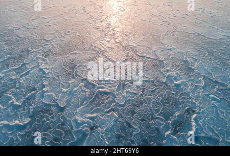 Vue aérienne de dessus en bas de la surface de glace. Texture de la surface de la mer gelée avec reflet du soleil Banque D'Images