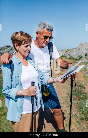 Couple senior avec poteaux trekking regardant la carte Banque D'Images