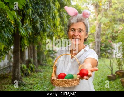 Femme âgée tenant le panier de Pâques avec des œufs dans l'arrière-cour Banque D'Images
