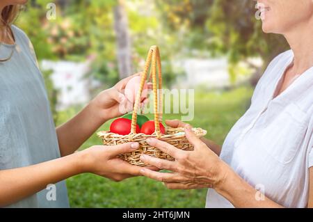 Femme aînée et jeune fille tenant un panier avec des œufs de pâques à l'extérieur Banque D'Images