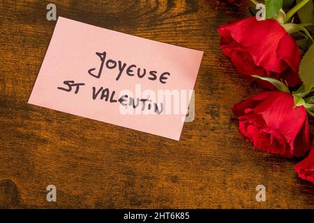 inscription happy saint valentin en français sur une étiquette avec un bouquet de roses rouges Banque D'Images