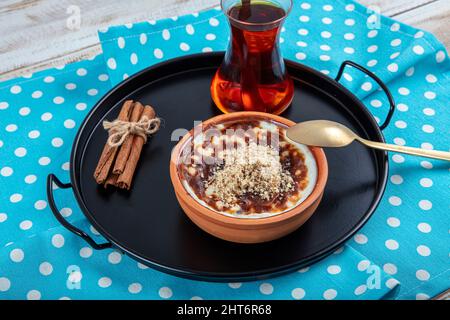 Riz cuit au lait turc dessert sutlac en cocotte avec bâtonnets de cannelle et noisettes. Pudding au riz à la cannelle et à la muscade. Pudding de riz, Banque D'Images