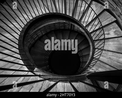 Escalier en colimaçon. Image en noir et blanc de l'escalier en bois et fer en spirale vers le bas à l'obscurité. Banque D'Images