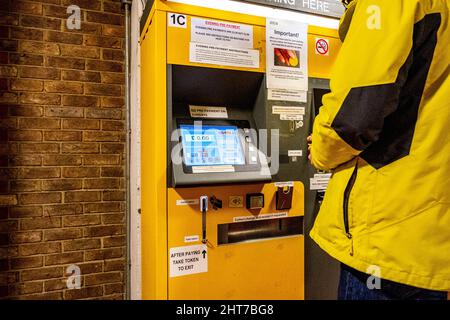 Epsom Surrey, Royaume-Uni, février 27 2022, un homme en gros plan paie des frais de stationnement à un distributeur automatique de paiement de stationnement Banque D'Images