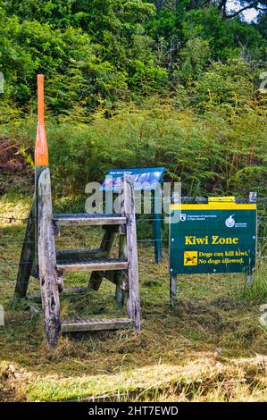 Un stile en bois et un panneau de zone Kiwi indiquant une zone de protection pour les kiwis. Sur un sentier à travers la forêt de Pukenui, Whangarei, Île du Nord, Nouvelle-Zélande Banque D'Images