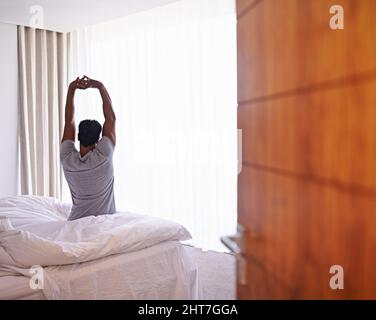 Les meilleures nuits de sommeil de ma vie. Un jeune homme qui s'étire après s'être réveillé. Banque D'Images