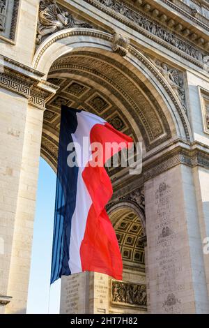 Un grand drapeau français flotte dans le vent sous la voûte de l'Arc de Triomphe à Paris, en France. Banque D'Images