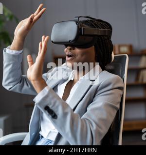 Choqué par VR noir femme d'affaires dans la réalité virtuelle gévalue regardant la vidéo à 360 degrés sur le lieu de travail Banque D'Images
