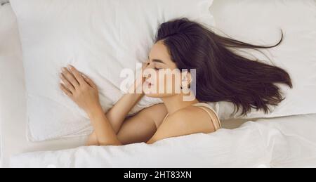 Vue de dessus d'une belle jeune femme détendue ayant une bonne nuit de repos dans son lit Banque D'Images