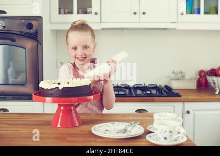 J'ai fait ce gâteau tout seul. Une petite fille mignonne à faire un gâteau dans la cuisine. Banque D'Images