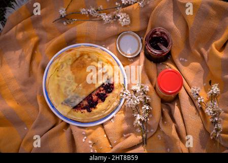 Une vue de dessus d'une confiture de crêpes maison placée sur une assiette sur une couverture dans un pique-nique dans l'herbe verte Banque D'Images