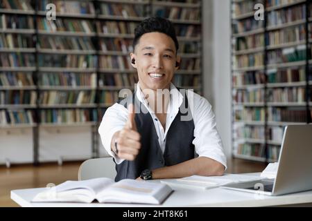 Un jeune homme heureux étudiant en Corée recommandant des cours en ligne. Banque D'Images