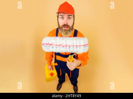 Peintre avec rouleau de peinture et cartouche. Concepteur ou constructeur professionnel en casque de sécurité et uniforme. Banque D'Images