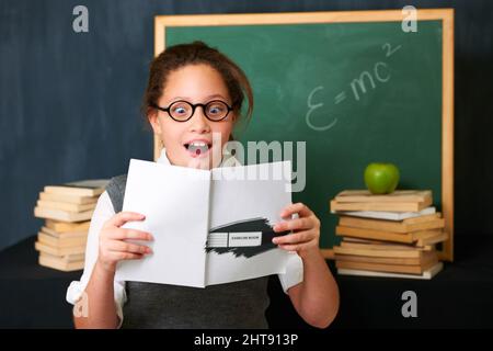 Wow ces exercices semblent amusants. Une jolie fille de brunette qui a l'air fascinée par le livre qu'elle tient. Banque D'Images