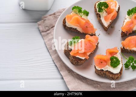 Mini sandwiches avec du saumon, du fromage caillé, du persil et du pain de seigle sous forme de coeurs.Saint-Valentin cuisine créative maison.J'adore le design du petit déjeuner.Séle Banque D'Images