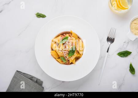 Pâtes de la Penne à la bolognaise.Savoureuses pâtes italiennes classiques appétissantes au parmesan, au basilic et à la sauce bolognaise dans une assiette blanche sur la pierre Banque D'Images