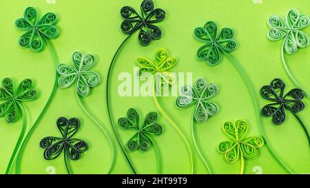 Le papier de Quilling est un papier qui se déverse sur fond vert. Arrière-plan de la Saint-Patrick avec des feuilles de trèfle et de trèfle fabriquées en papier filigrane. Banque D'Images