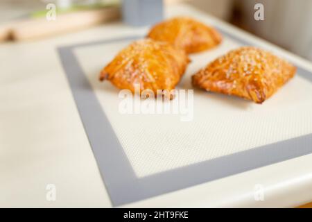 samsa fraîchement cuit hors de l'accent sur un tapis de cuisson sur la table de cuisine avec l'espace de copie. Banque D'Images