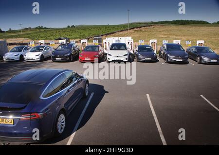 Voitures électriques Tesla garées aux points de recharge situés au chargeur Tebay Southbound sur l'autoroute M6 près de Penrith dans le nord de l'Angleterre Banque D'Images