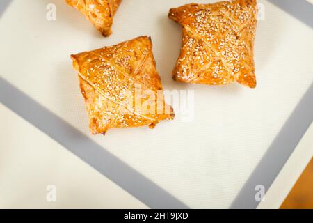 Vue de dessus de la pâtisserie de la samosa fraîchement cuite sur le tapis de cuisson sur la table de cuisine avec espace de copie. Banque D'Images