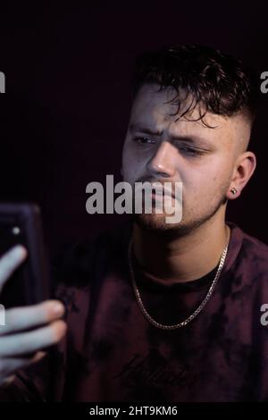Photo verticale d'un homme contrarié lisant des informations sur son smartphone Banque D'Images