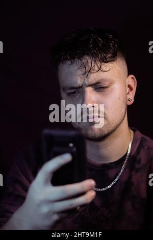 Photo verticale d'un homme contrarié lisant des informations sur son smartphone Banque D'Images