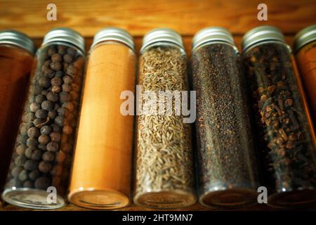 Gros plan sur un ensemble de différentes épices dans des pots transparents - poivre, paprika, zira et clous de girofle. Banque D'Images