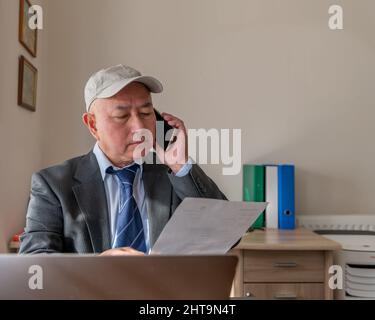 Un cadre supérieur au bureau au téléphone discutant d'un contrat avec un client. Banque D'Images