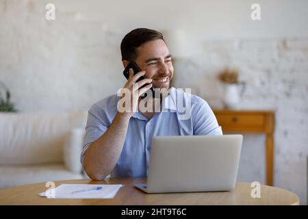 L'homme aime la conversation agréable sur smartphone sourires regarde dans la distance Banque D'Images