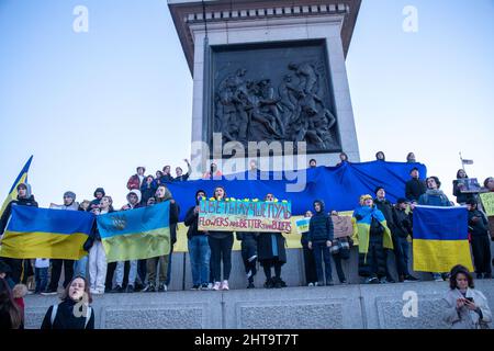 LONDRES, FÉVRIER 27 2022 les manifestants pro-Ukraine détiennent le drapeau ukrainien sur la colonne de Nelson alors qu'ils protestent contre l'invasion de l'Ukraine par la Russie sur Trafalgar Square. Crédit : Lucy North/Alamy Live News Banque D'Images