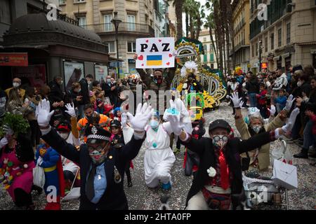 Malaga, Espagne. 27th févr. 2022. Un homme habillé comme un soldat ukrainien est vu portant un écriteau qui dit « paix » tandis que d'autres montent les bras pendant le défilé de carnaval.les fêtards et les chars prennent les rues à Malaga célébrant le carnaval depuis le relâchement des restrictions pendant la pandémie de la maladie de COVID-19. Des milliers de personnes célèbrent le carnaval habillé comme des personnages différents ou représentant des problèmes sociaux. (Photo de Jesus Merida/SOPA Images/Sipa USA) Credit: SIPA USA/Alay Live News Banque D'Images