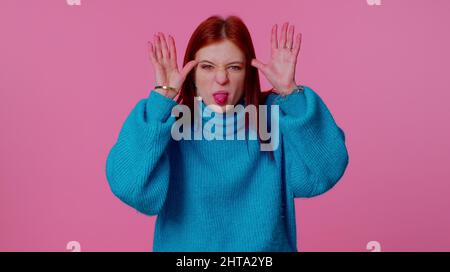 Joyeux portrait amusant de l'adolescente étudiante fille en chandail bleu montrant la langue faire des visages à l'appareil photo, se tromper autour, plaisantant, en béant avec le visage stupide, Banque D'Images