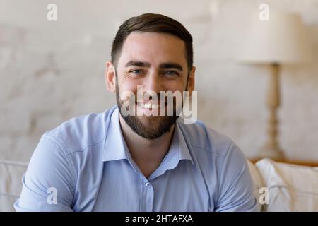 Beau homme assis sur le canapé à la maison regarder la caméra Banque D'Images