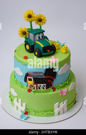 Photo de gâteau fondant sur le thème de la ferme verte avec un camion, des poussins et des tournesols Banque D'Images