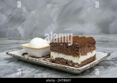 Tranche de tiramisu et crème glacée dans un plat de service en porcelaine Banque D'Images