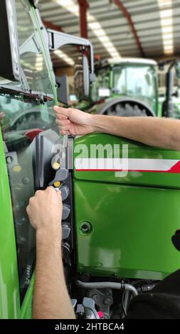 Gros plan d'un mécanicien agricole travaillant sur un tracteur agricole vert dans l'atelier de mécanicien Banque D'Images