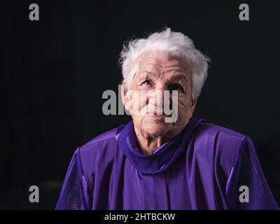 Portrait d'une femme âgée sérieuse sur fond noir Banque D'Images