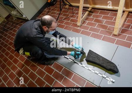 Schleswig, Allemagne. 20th janvier 2022. Un employé de l'atelier central archéologique de la Fondation des Musées d'Etat du Schleswig-Holstein manque des parties d'un naufrage vieux de plusieurs siècles au château de Gottorf. L'épave a été découverte dans le fleuve Lippe en Rhénanie-du-Nord-Westphalie en 2019. Credit: Axel Heimken/dpa/Alay Live News Banque D'Images