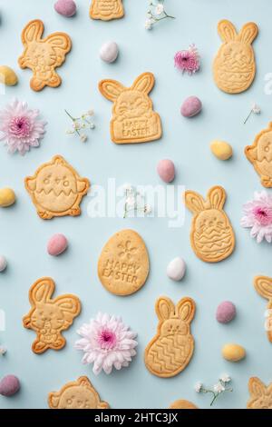 Biscuits au sucre en forme de lapin avec œufs au chocolat de Pâques et fond de fleurs. Joyeuses Pâques Banque D'Images