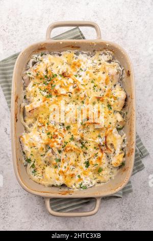 Cocotte de poisson blanc, chou-fleur, pomme de terre au fromage, crème sure et oignon Banque D'Images