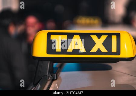 Petit foyer d'un panneau JAUNE DE TAXI sur le dessus d'une voiture de taxi avec des gens flous dans l'arrière-plan Banque D'Images