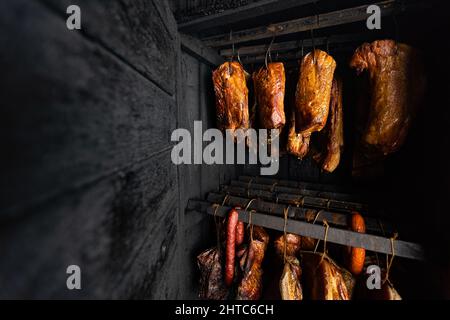 Gros plan de la viande fumée et du ventre ou de la viande de hêtre avec croûte foncée dans le fumoir ou fumoir, concept alimentaire Banque D'Images