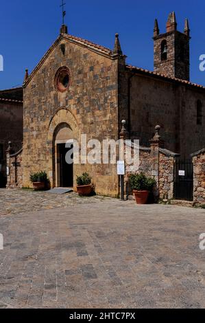 Un oculus rond bordé de pierces en terre cuite sculptées la façade romane dorée du début du 13th siècle Chiesa di Santa Maria Assunta sur la Piazza Roma, Monteriggioni, Toscane, Italie. Banque D'Images