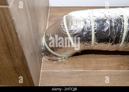 Admission d'air et échappement dans la ventilation mécanique domestique avec récupération de chaleur avec tuyaux isolés visibles avec feuille d'argent entrant dans le mur. Banque D'Images