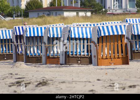 Chaises de plage en bois avec des couvertures en tissu bleu et blanc dans une plage de sable Banque D'Images