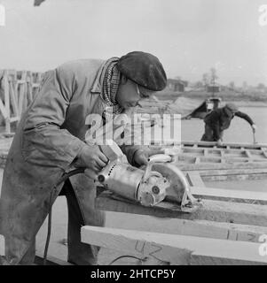 RAF Gaydon, Gaydon, Stratford-on-Avon, Warwickshire, 11/03/1953. Un ouvrier utilisant une scie circulaire électrique pour couper du bois pour la construction de bâtiments à Gaydon Airfield. Les travaux de construction d'une nouvelle piste à l'aérodrome de Gaydon ont commencé au début de 1952. Ce contrat a été suivi d'un deuxième contrat pour la construction de plus de 100 bâtiments du Ministère de l'air et de l'Easiform, et de 23 refuges de Nissen. Banque D'Images